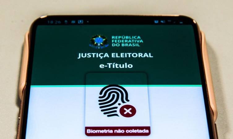 Celular com o aplicativo e-Título aberto e aviso de biometria não coletada.